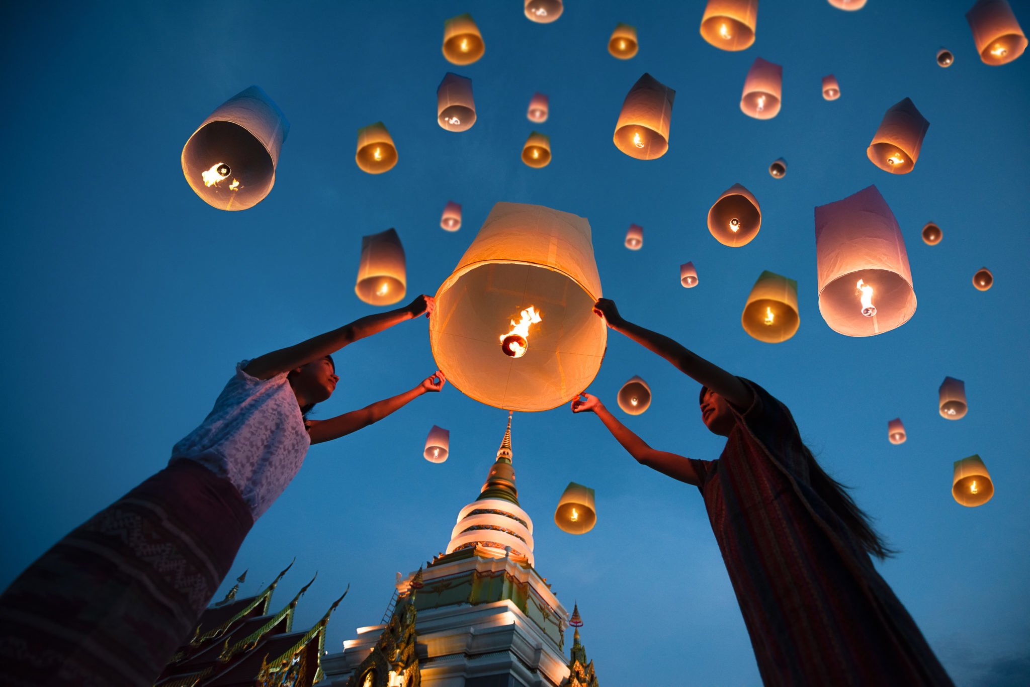 Dwie kobiety puszczające lampion do nieba wieczorową porą, w świątyni buddyjskiej
