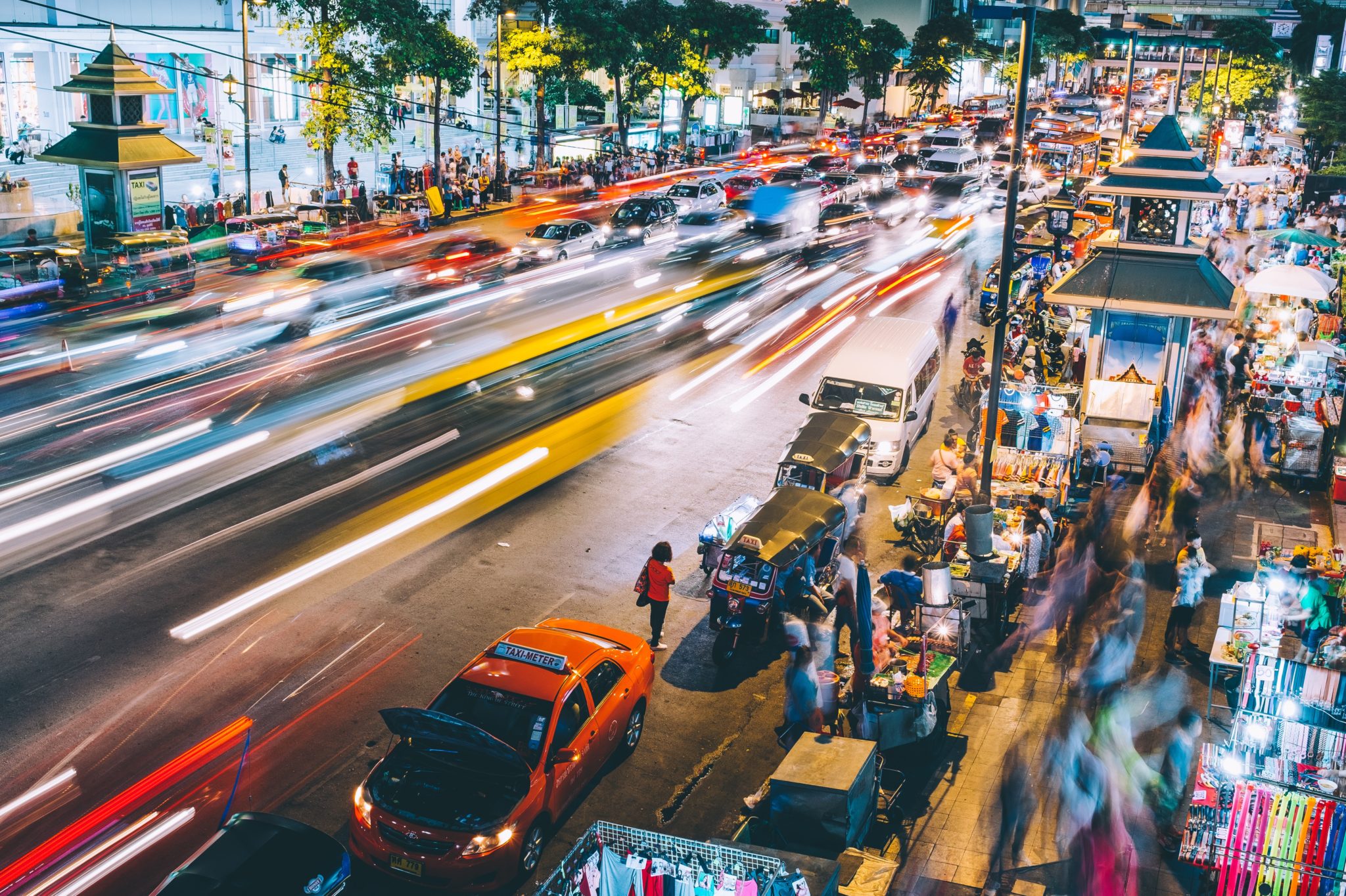 Ruch uliczny w Bangkoku nocą, nocny market, dużo taksówek, tuk tuków, przechodniów, jedzenie uliczne, stragany