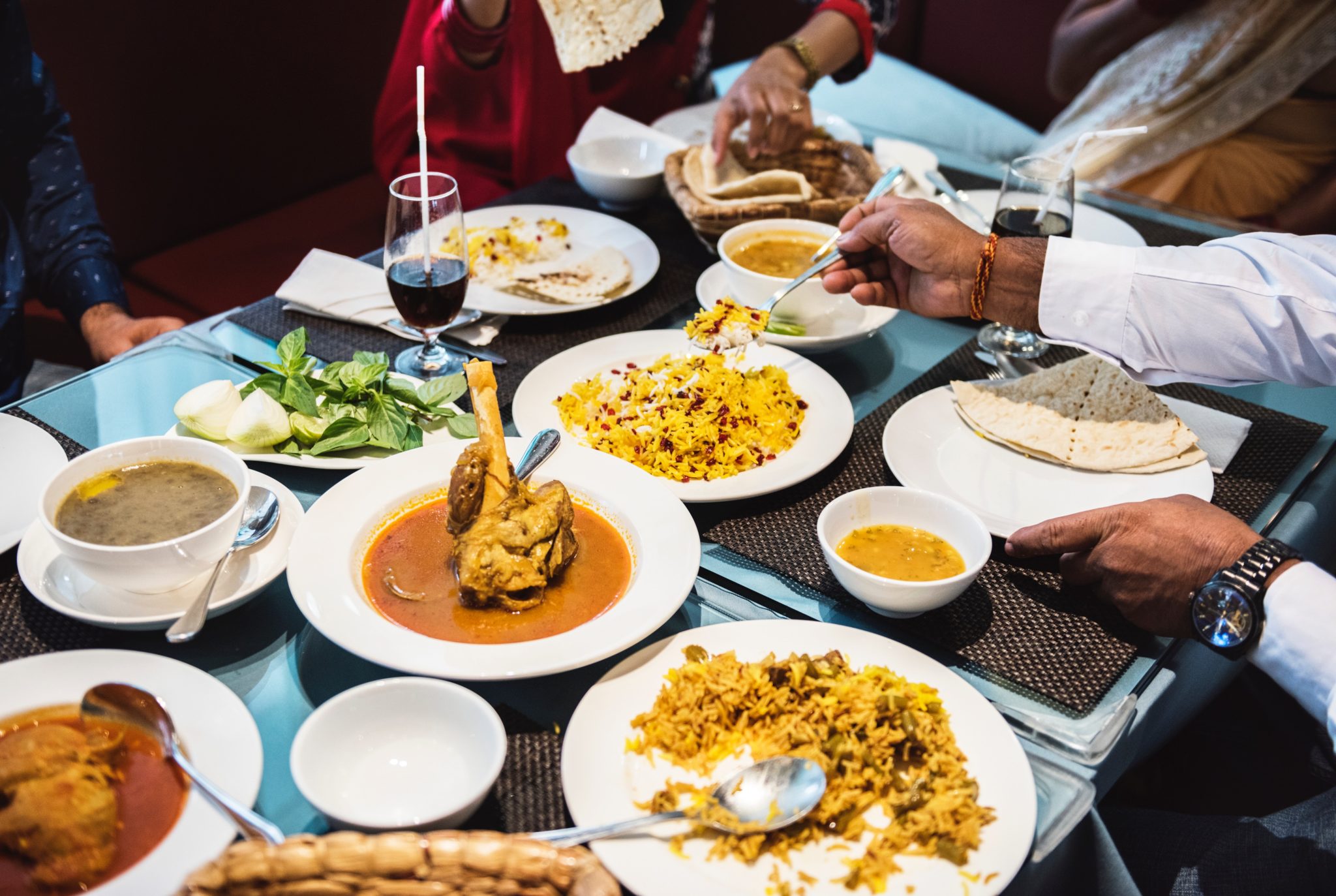 Stół zastawiony daniami kuchni azjatyckiej curry z kurczakiem, wonton, ryż z warzywami