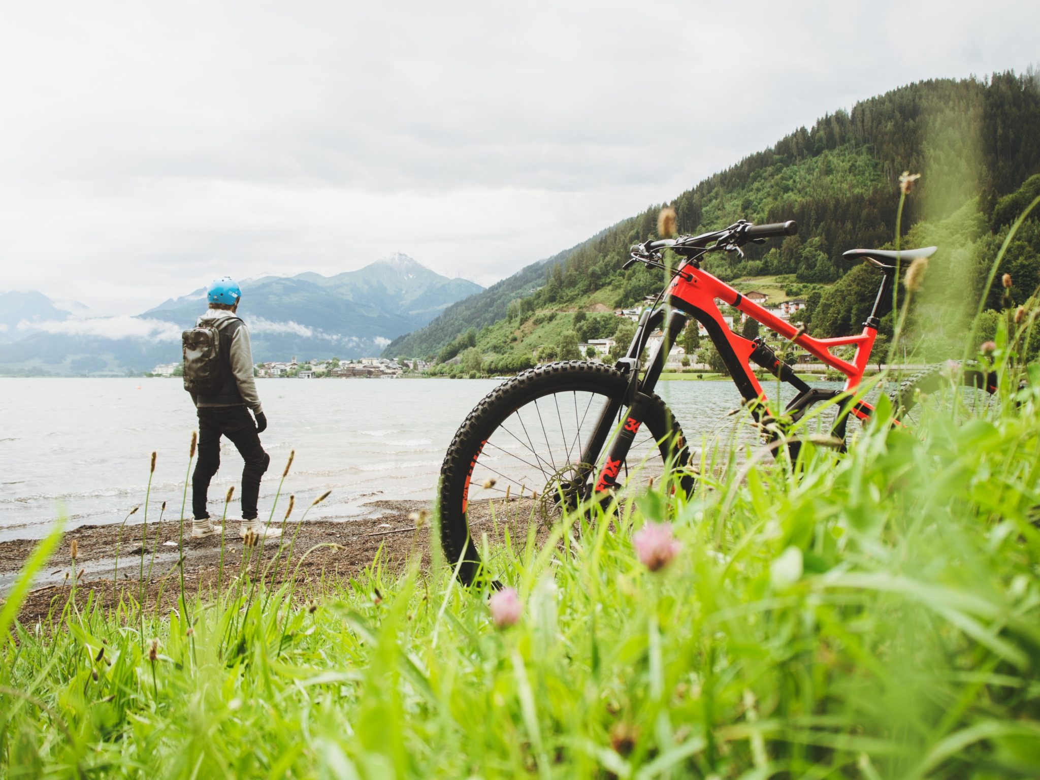 Mężczyzna w kasku stojący nad jeziorem obok rower, wycieczka rowerem