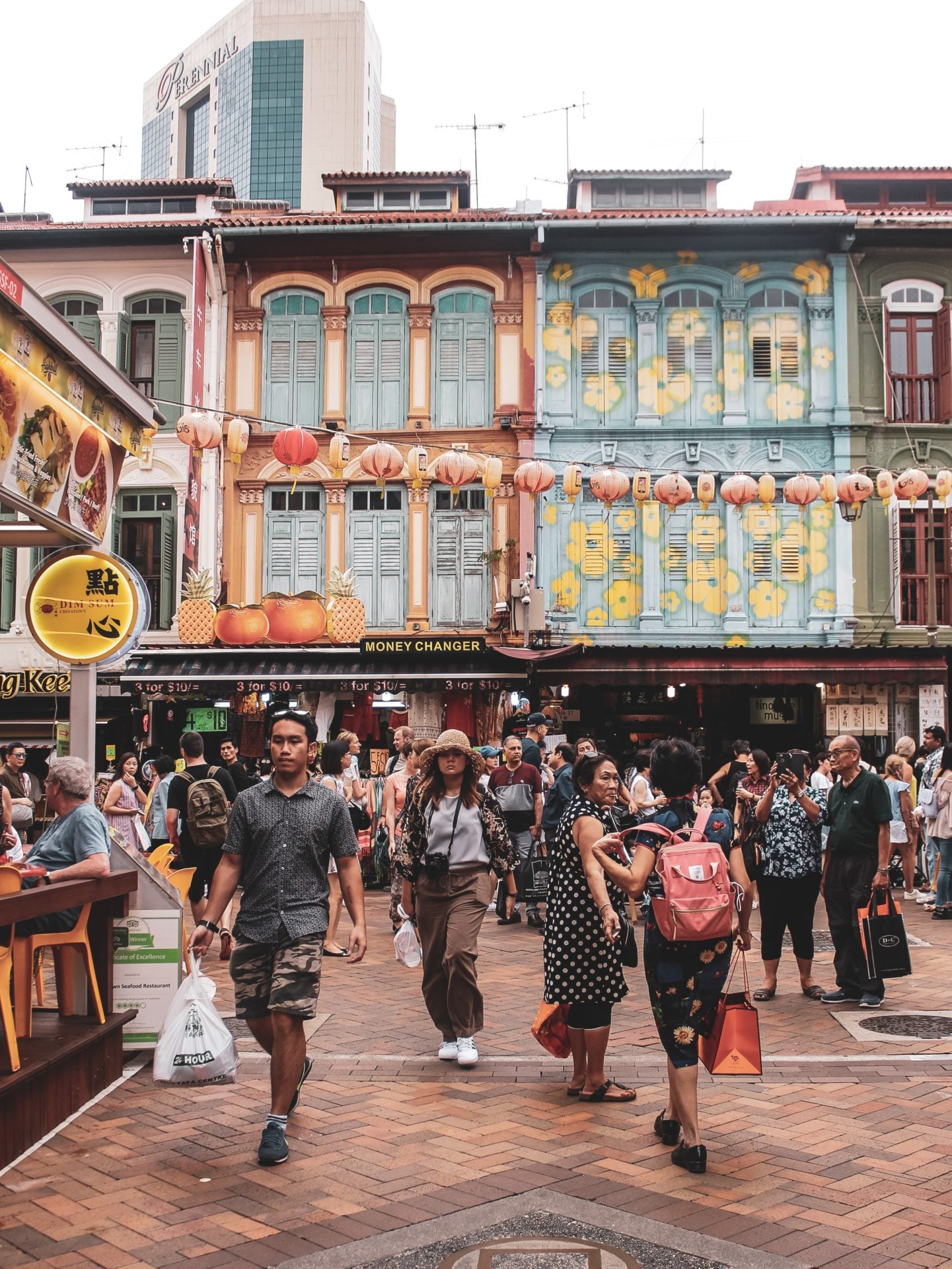 Ludzie robiący zakupy na markecie w Dzielnicy Chińskiej w Singapurze na tle kolorowych kamienic