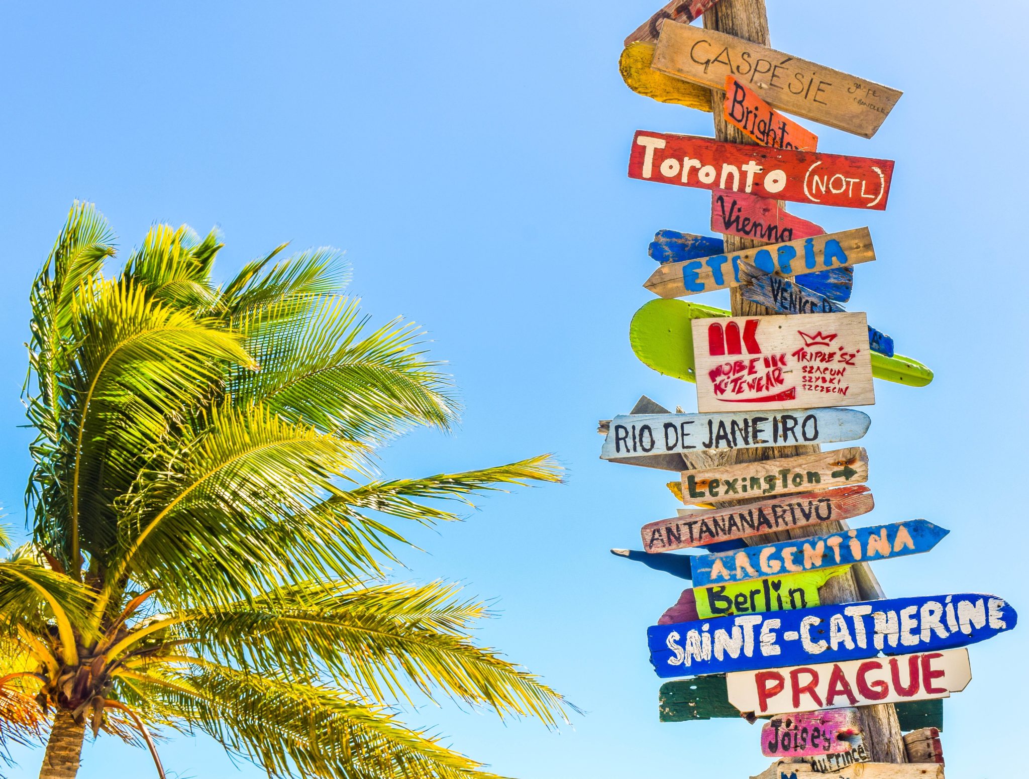 tabliczki z różnymi kierunkami podróży na plaży Long Bay Beach, na wyspach Turks i Caicos Islands