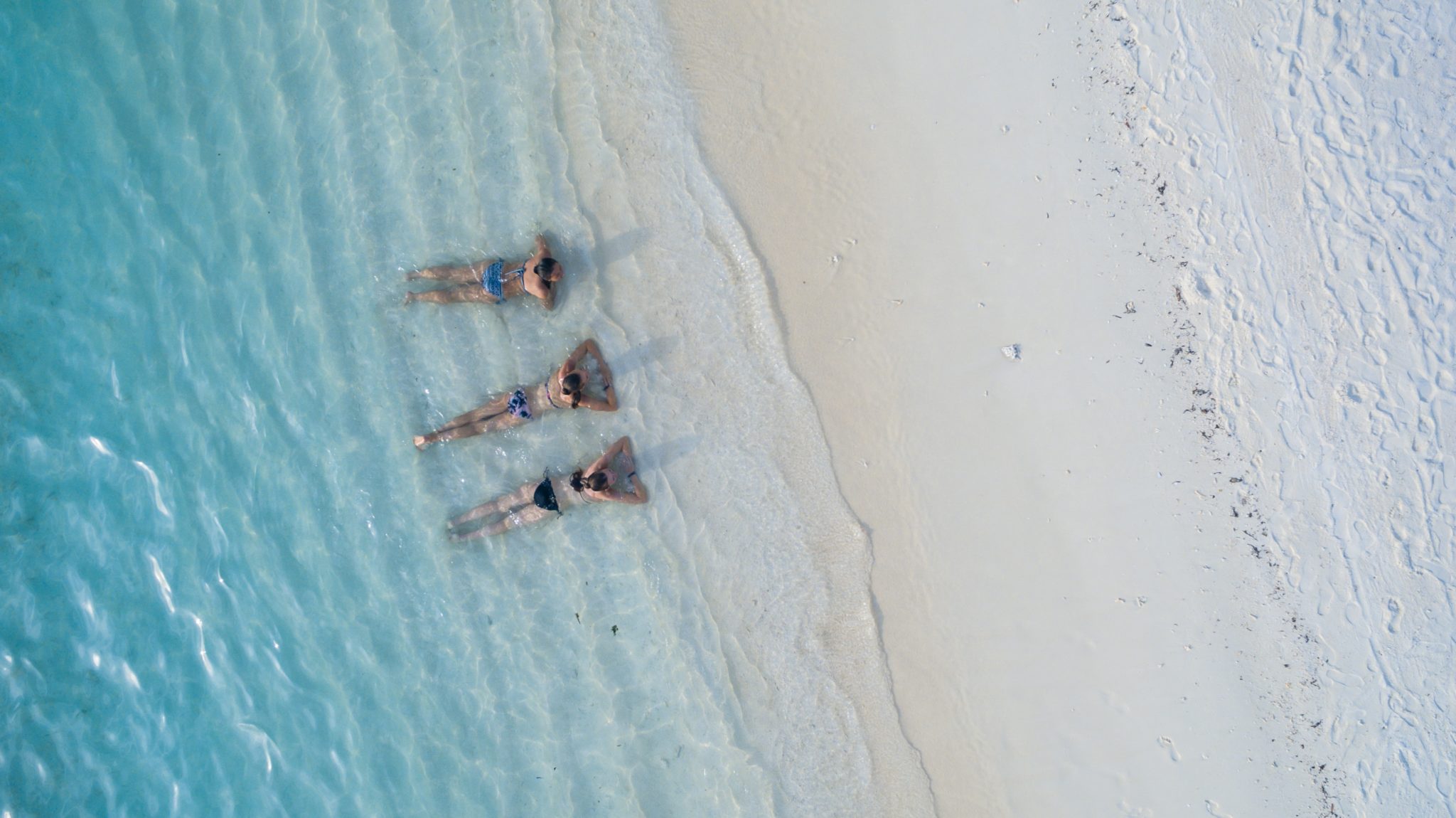 Trzy kobiety leżące na rajskiej plaży, turkusowa woda, biały piasek na Malediwach