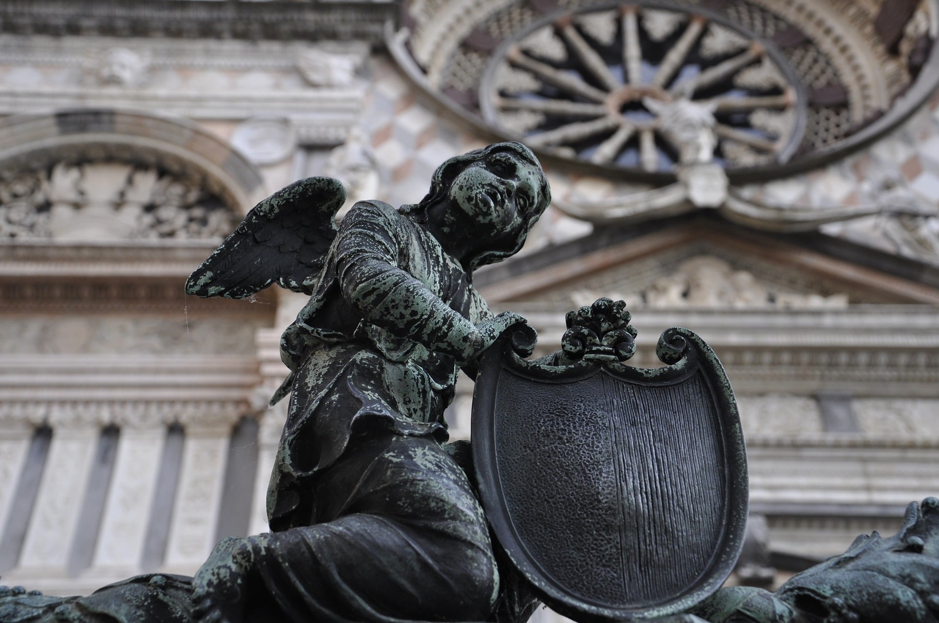 Figura anioła z tarczą przed kościołem w Bergamo