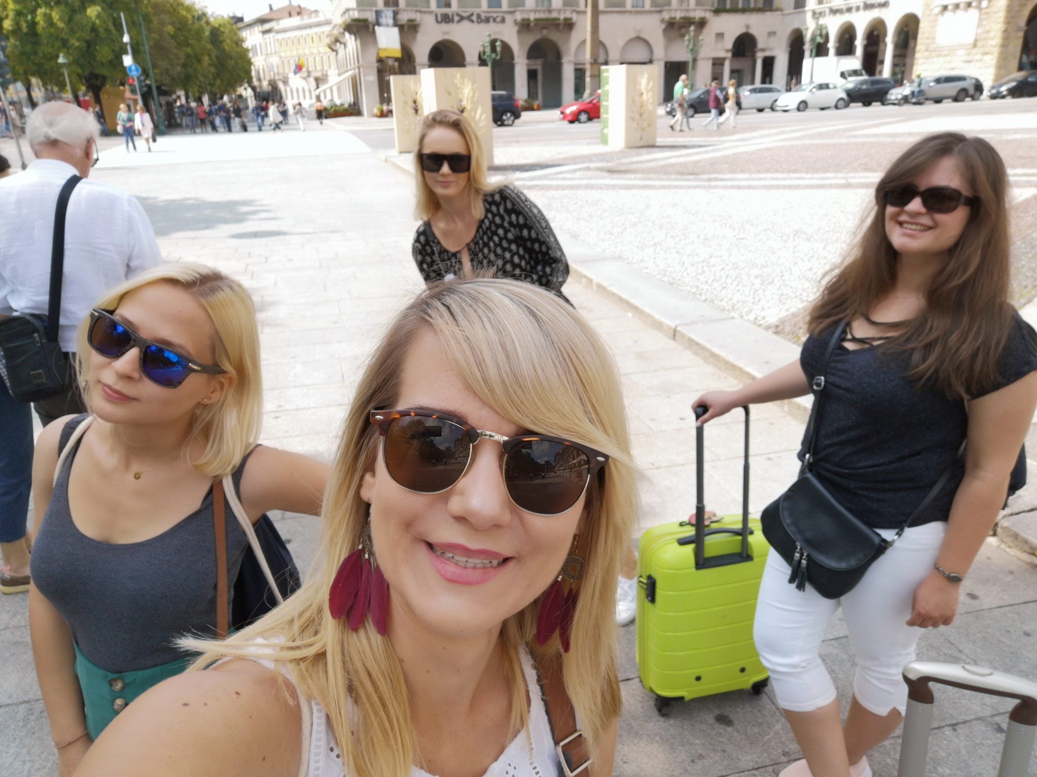 Cztery dziewczyny z walizkami stojące na pięknym, włoskim placu w mieście Bergamo
