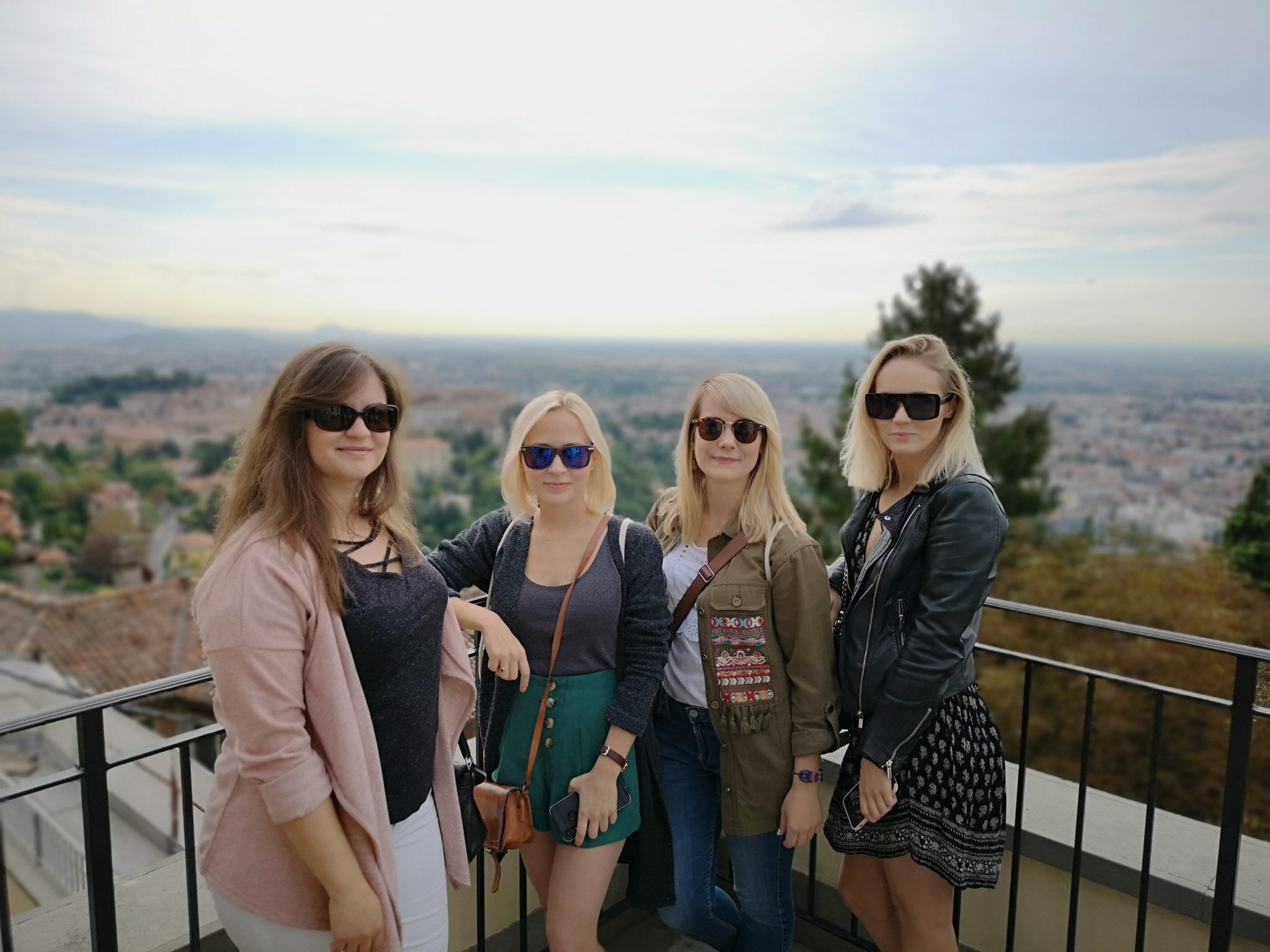 Cztery dziewczyny stojące na tarasie widokowym i pozujące do zdjęcia, w tle wspaniała panorama na Bergamo