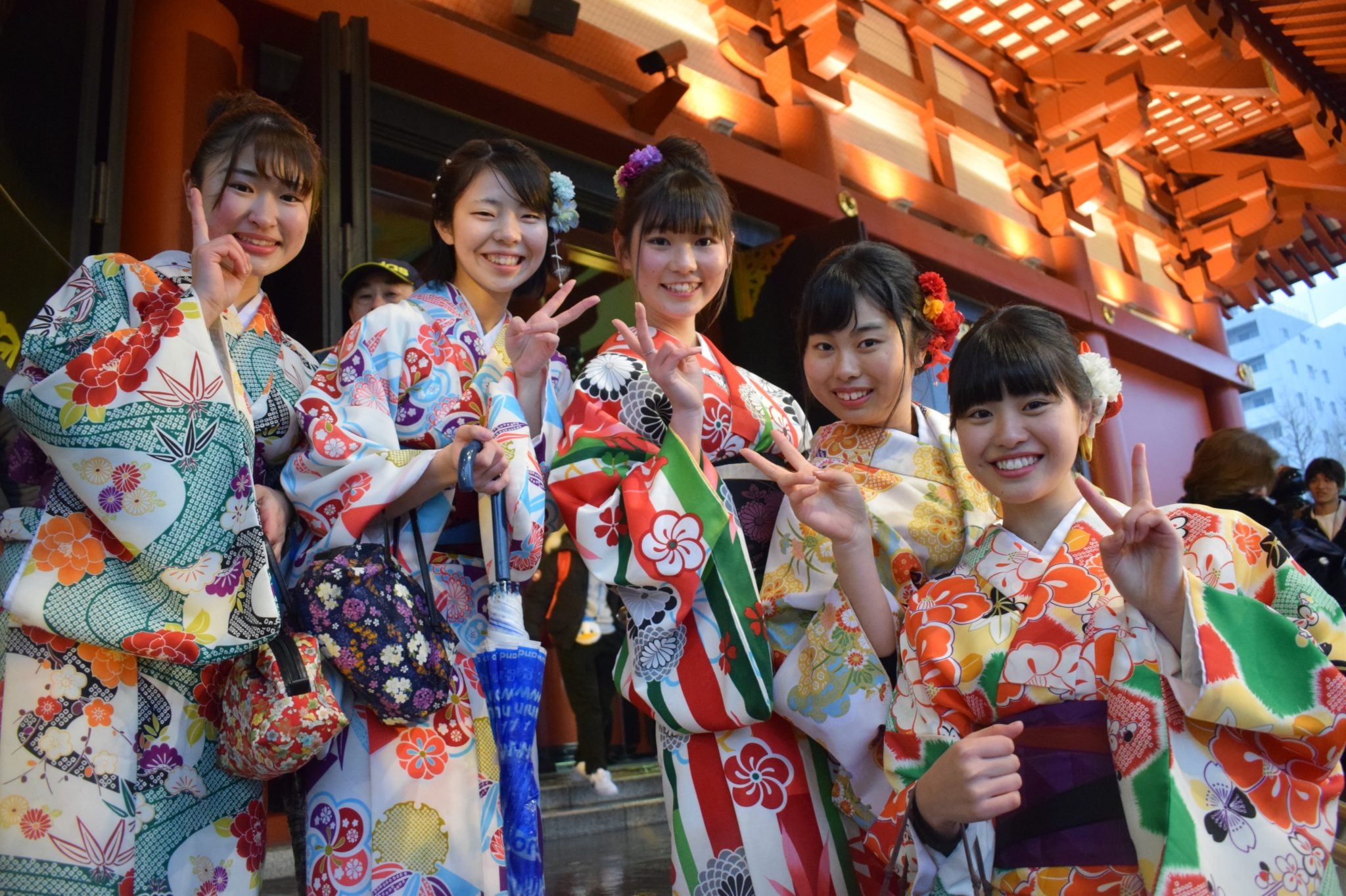 Pięć dziewzyn ubranych w kolorowe tradycyjne kimona pozujących do zdjęcia w świątyni