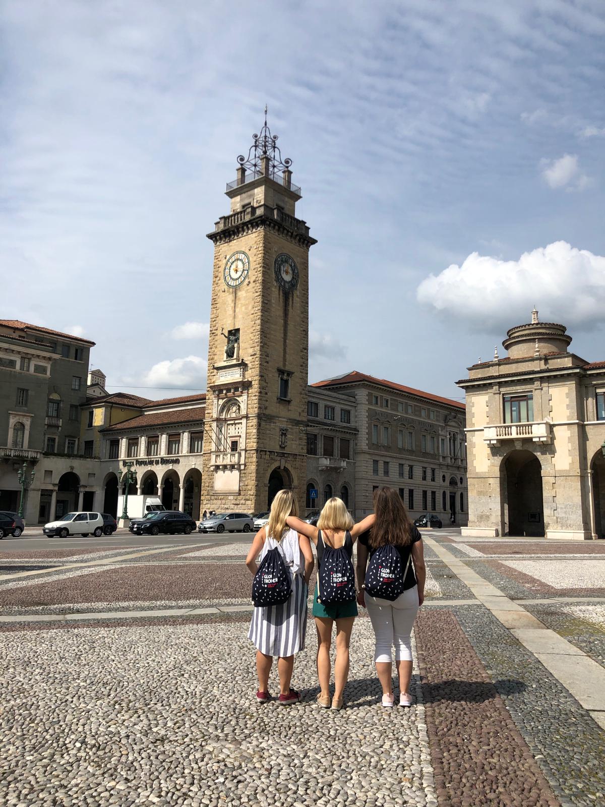 Trzy dziewczyny stojące na włoskim placu pod Wieżą Poległych - Torre dei Caduti - w mieście Bergamo