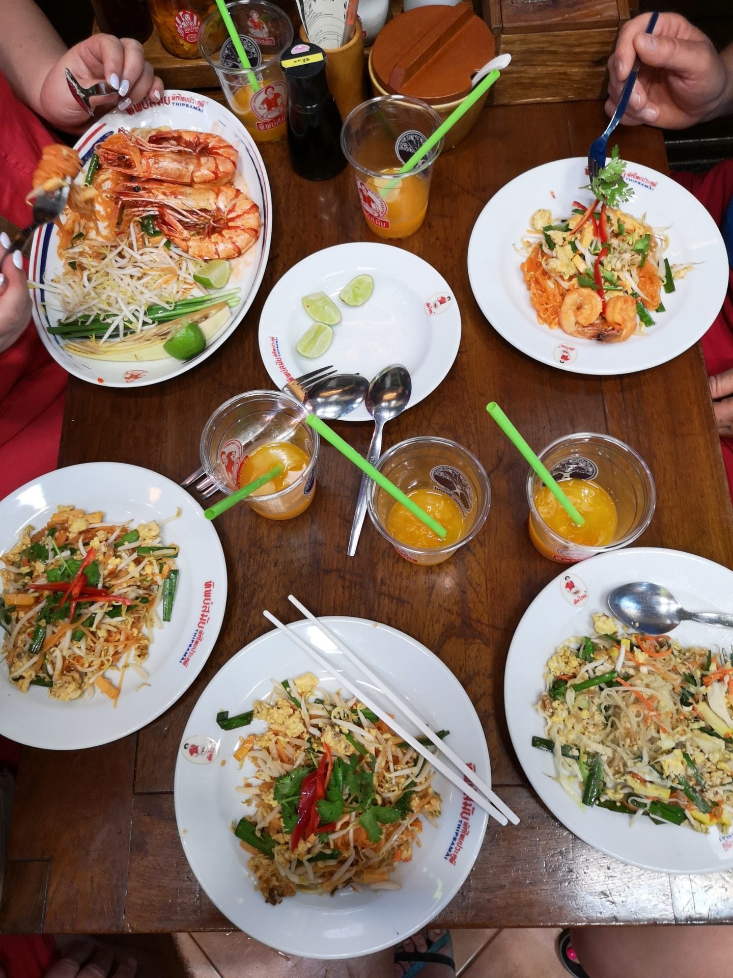 Stół na którym talerze z makaronem ryżowym i warzywami i krewetkami - pad thai