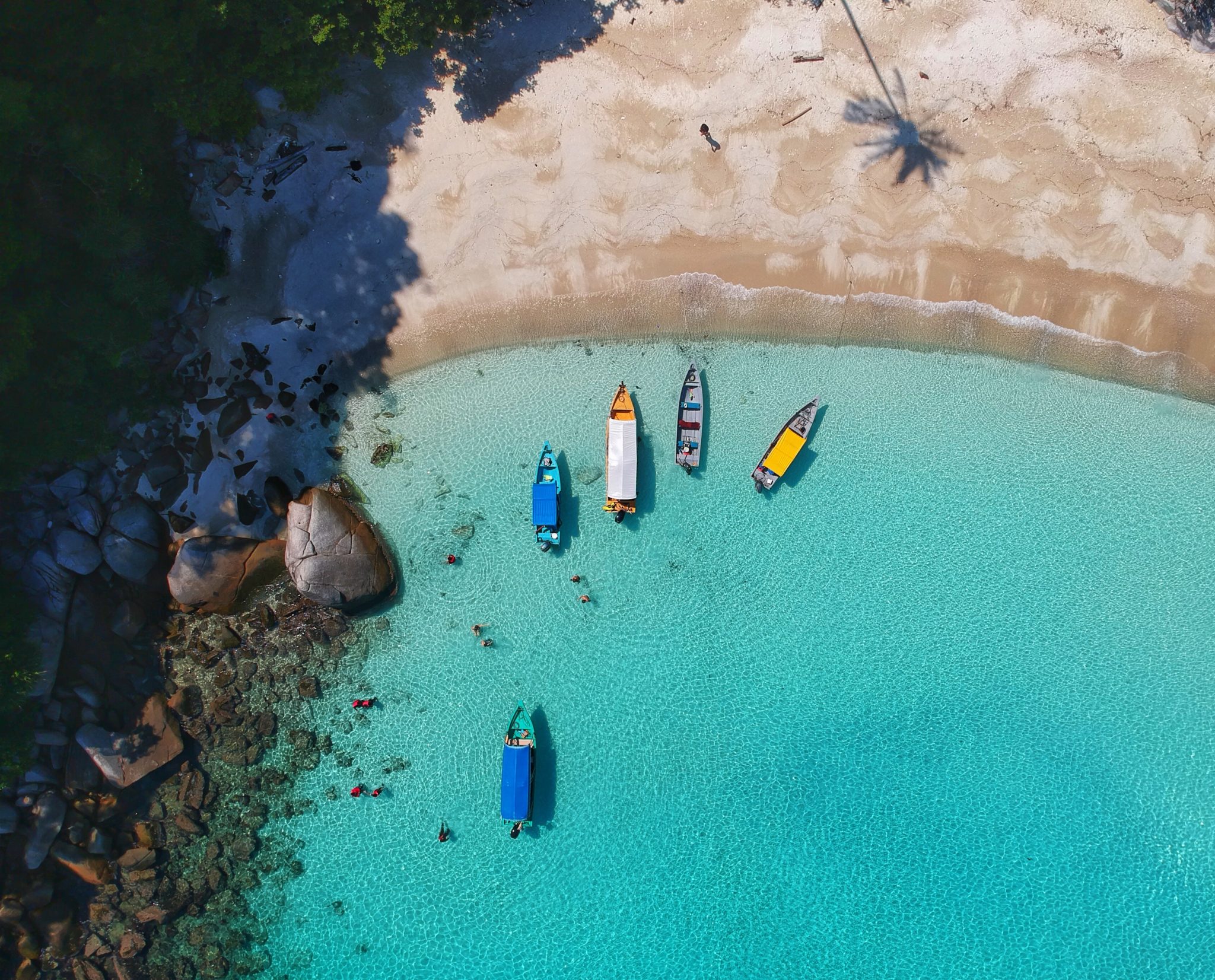 Widok z drona na plażę i lazurowe morze na malajskiej wyspie Perhentian, kilka kolorowych łodzi i palmy