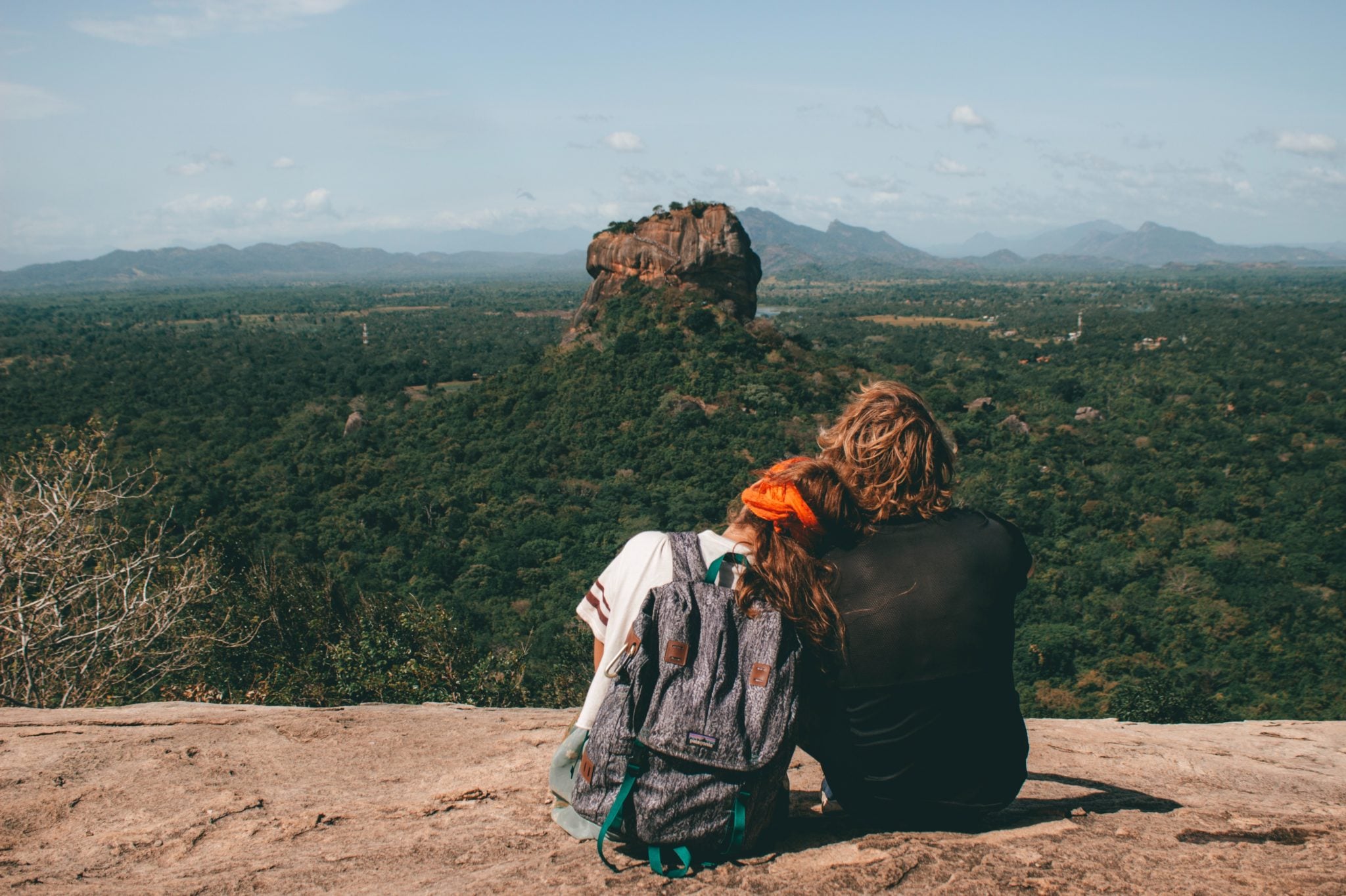 Para, dziewczyna i chłopak, siedzący i przytuleni spoglądający na lwią skałę na Sri Lance
