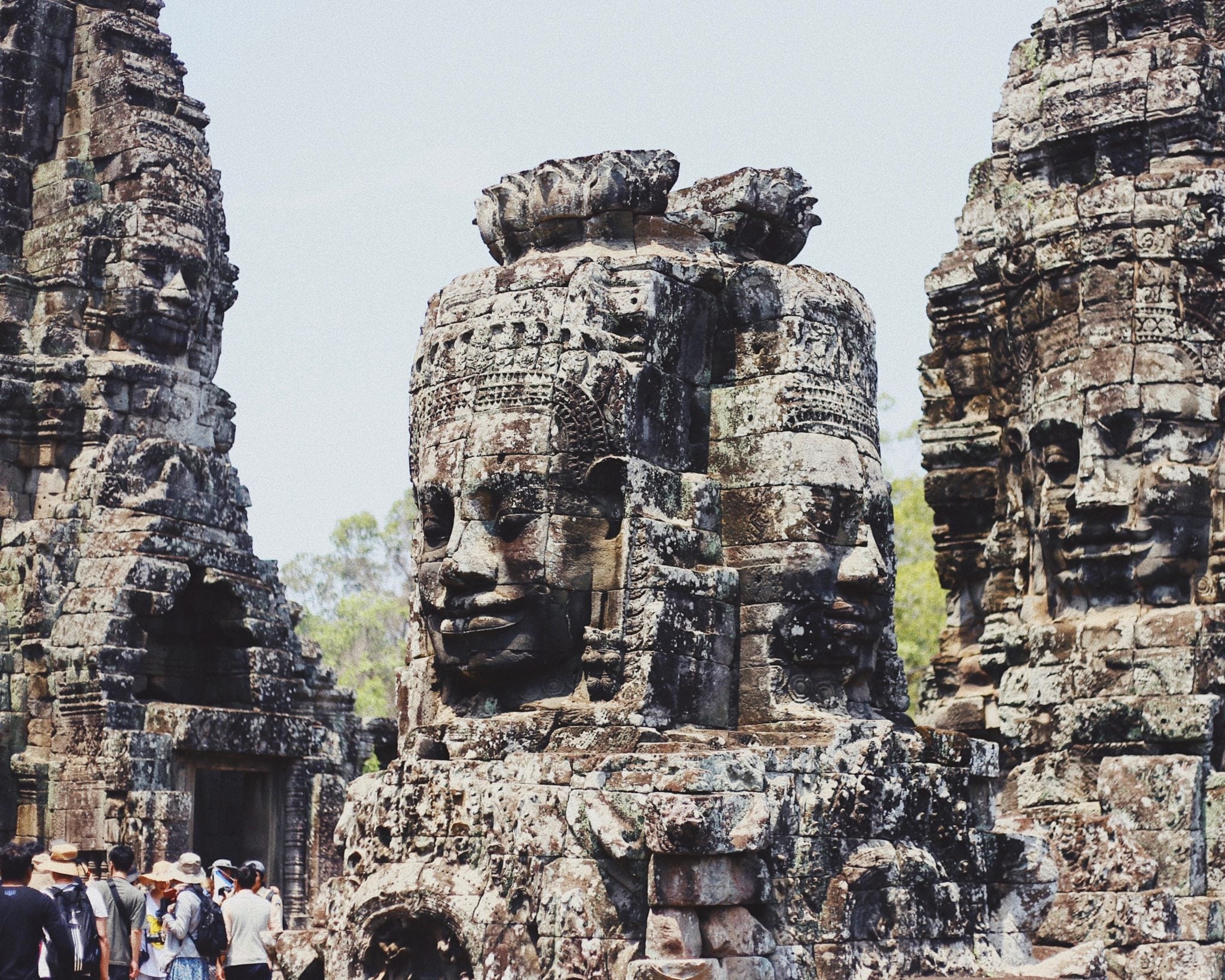 niebieskie niebo, statuy rzeźby z wielkimi głowami w kompleksie Angkor w Kambodży