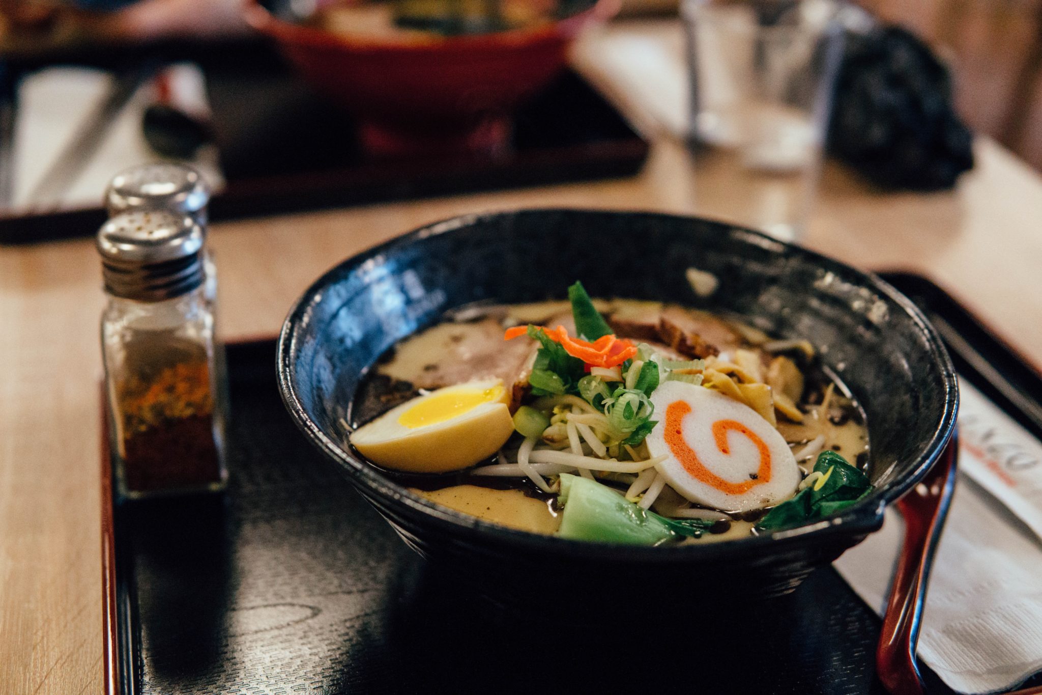 zupa ramen w japońskiej restuaracji, restauracja, zupa ramen w czarnej misce na stole, pałeczki